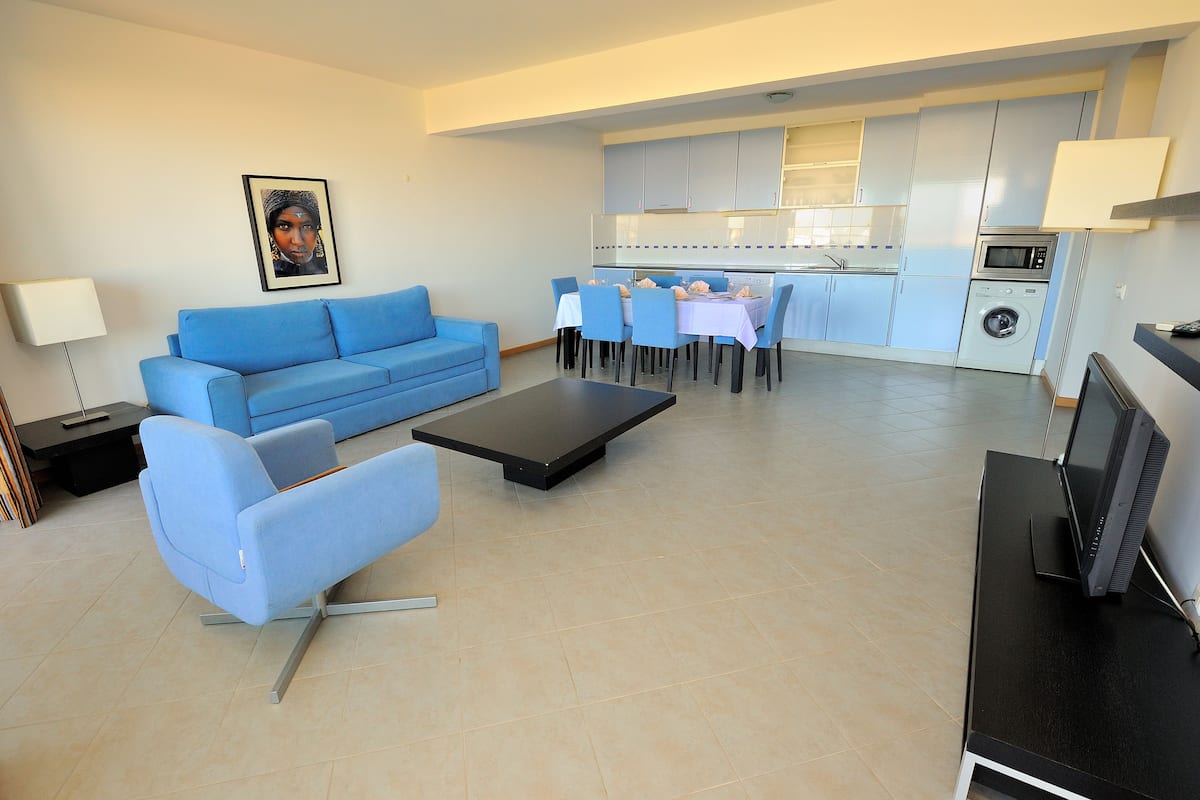 Un soggiorno moderno con un divano blu, un tavolino da caffè e una TV su un mobile.
