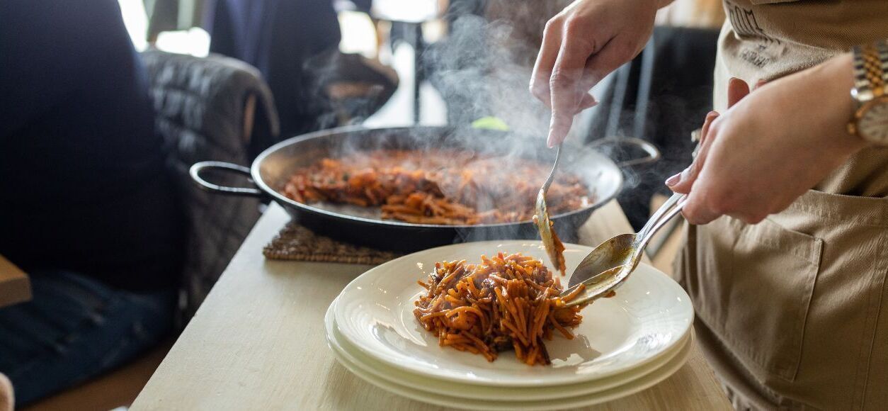 A person serving food from a pan to a plate.