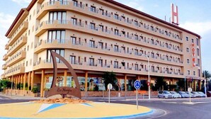 A multi-story hotel with balconies, a prominent 'HOTEL' sign, and a roundabout with a blue center.