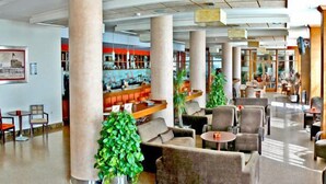 A spacious lobby with seating areas, a bar, and a large plant.