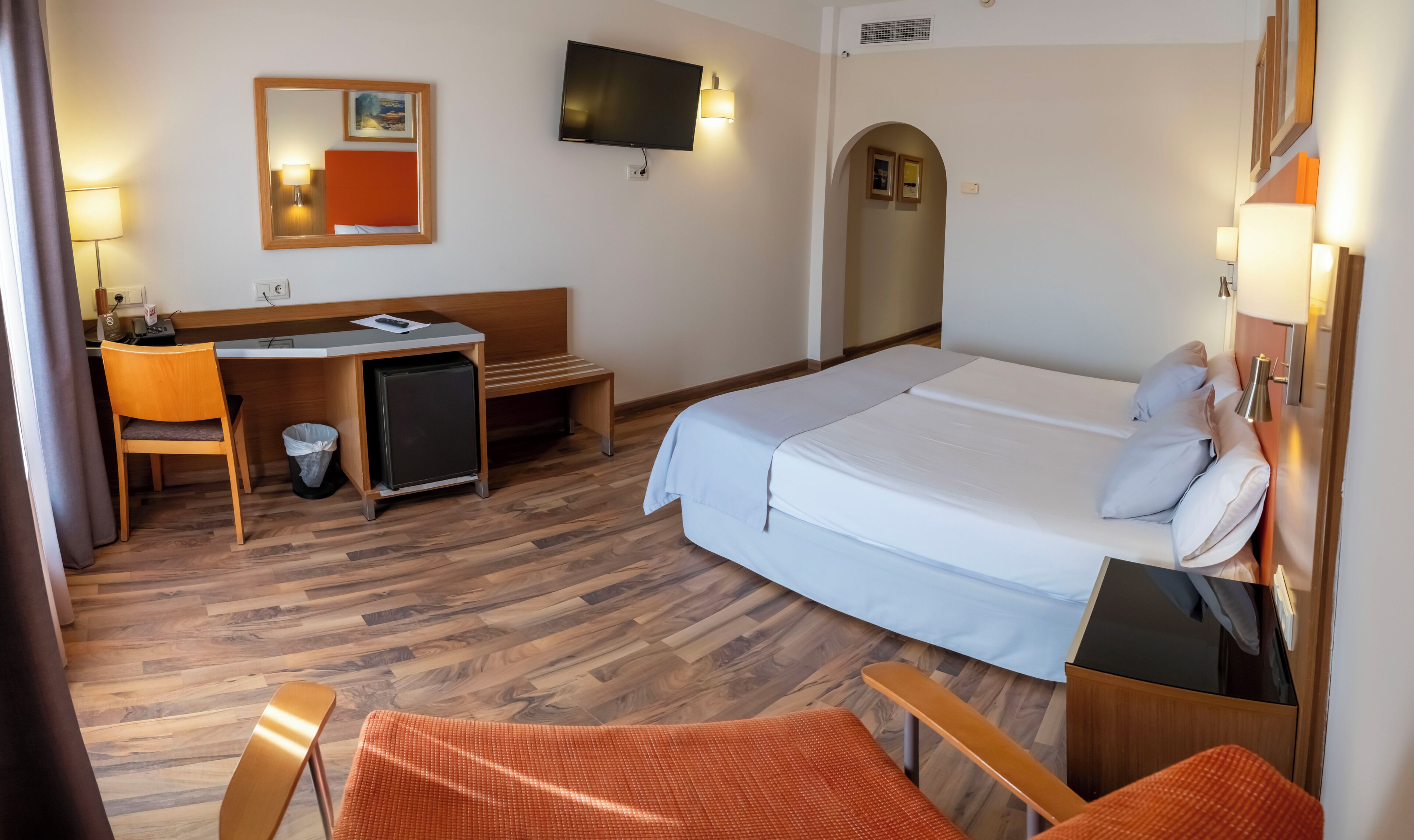 Een hotelkamer met een bed, bureau, stoel en televisie.