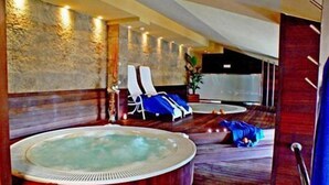 A spa area with a hot tub, two lounge chairs, and a potted plant.