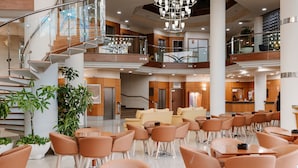 A spacious indoor area with multiple levels, featuring a central staircase, seating areas, and a reception desk. - Hotel Las Gaviotas (Cartagena)