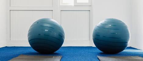 Two exercise balls on mats in a room with a blue carpet and white walls.
