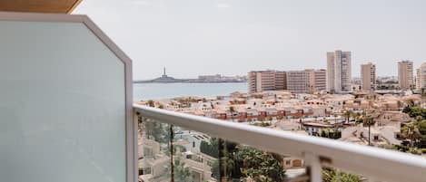 A balcony with a view of a coastal cityscape, including buildings and a lighthouse.
