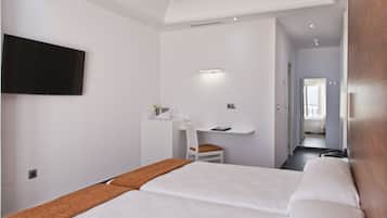 A hotel room with a large bed, a desk with a chair, a television mounted on the wall, and a bathroom visible through an open door.