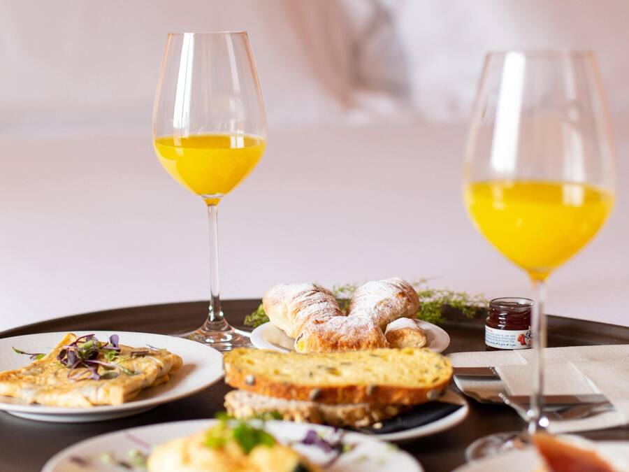 A breakfast tray with various dishes and two glasses of orange juice on a table in a hotel room.