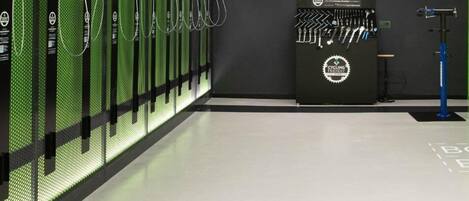 Un espacio interior moderno con una fila de objetos cilíndricos de color verde, posiblemente servidores o equipos, y un soporte de herramientas fijado a la pared con diversos objetos.