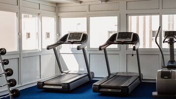 Un gimnasio con cintas de correr, una máquina de remo y equipo de levantamiento de pesas.