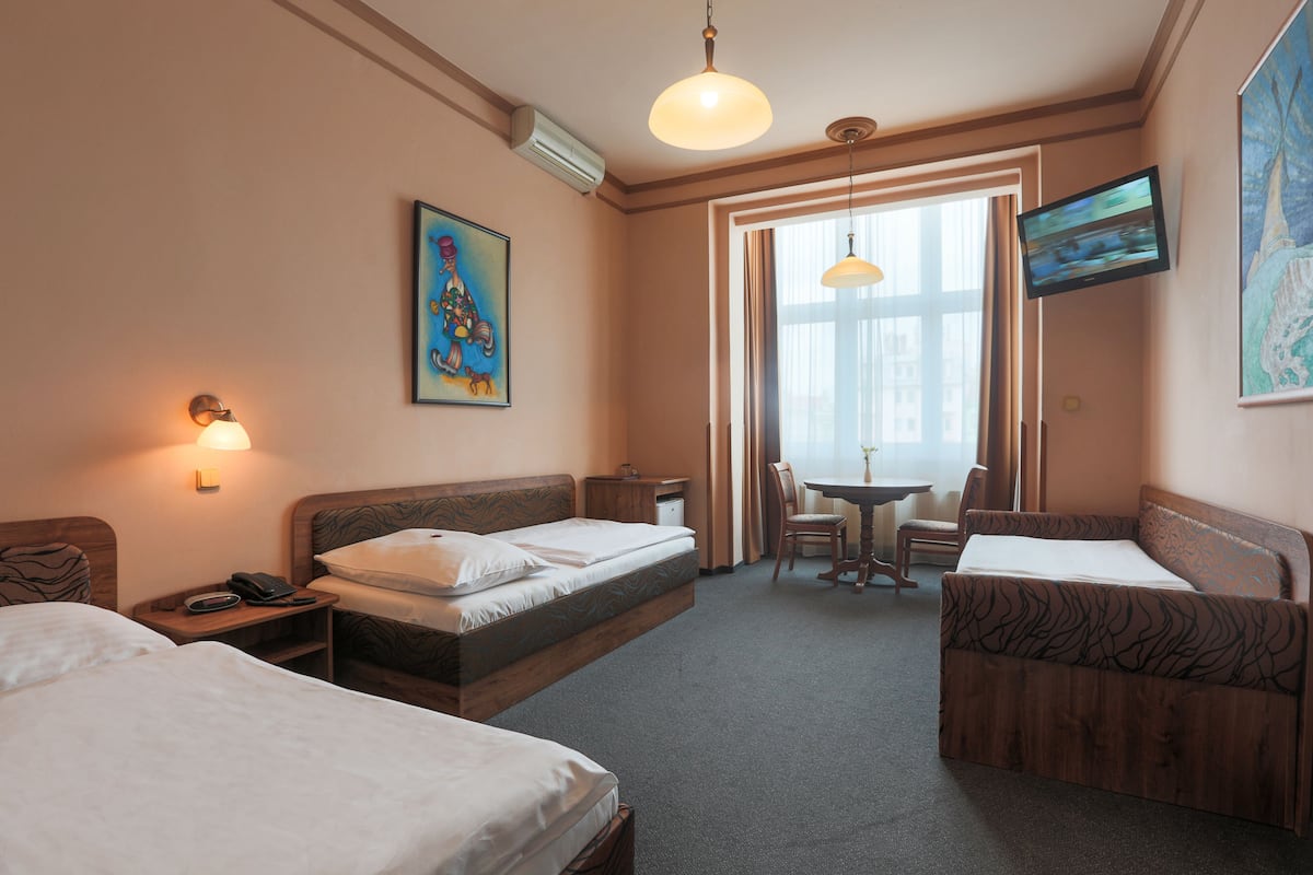 Habitación de hotel con dos camas, un escritorio, una silla, un televisor y un cuadro en la pared.