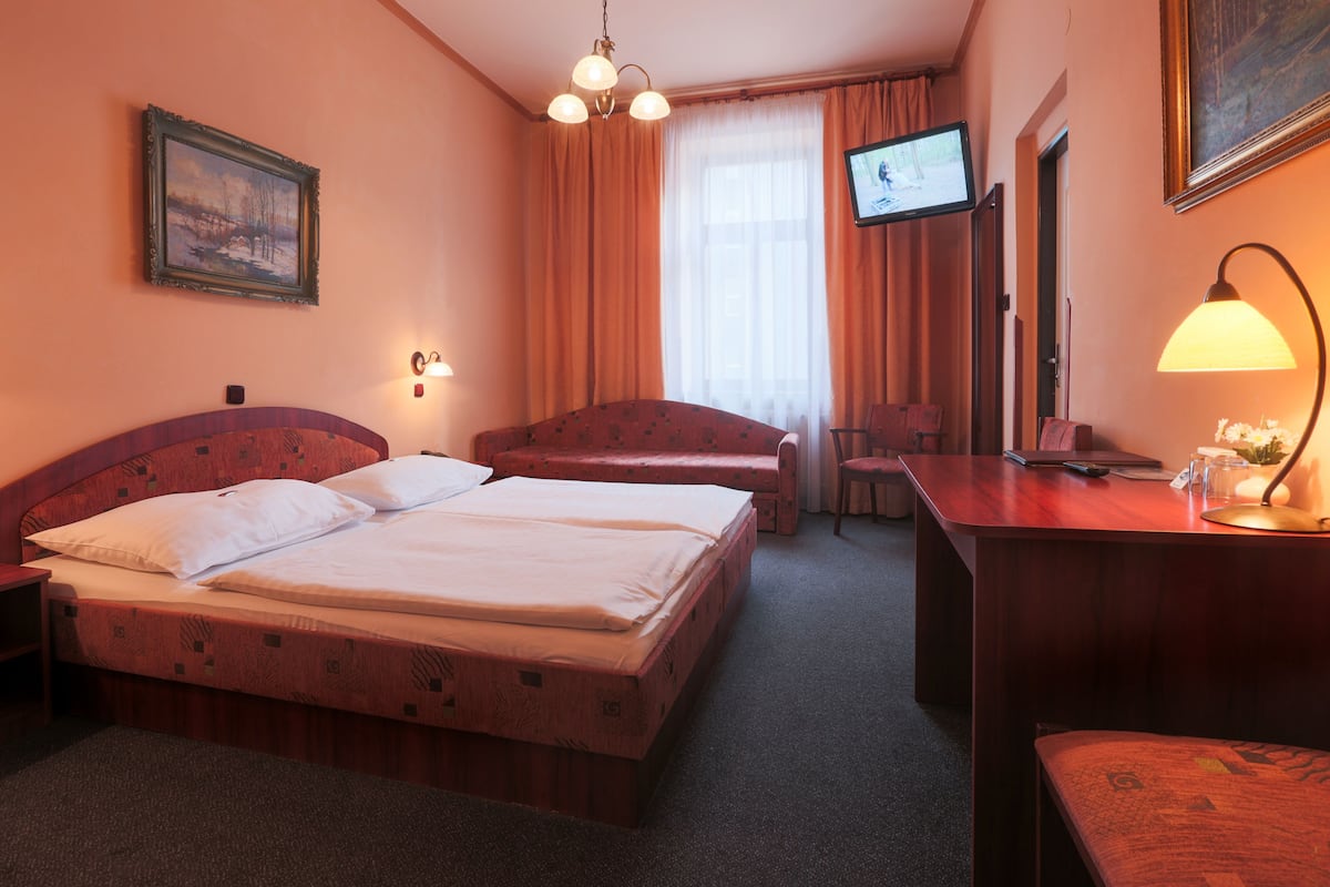 Habitación de hotel con dos camas, un escritorio, una silla, un televisor y una lámpara.
