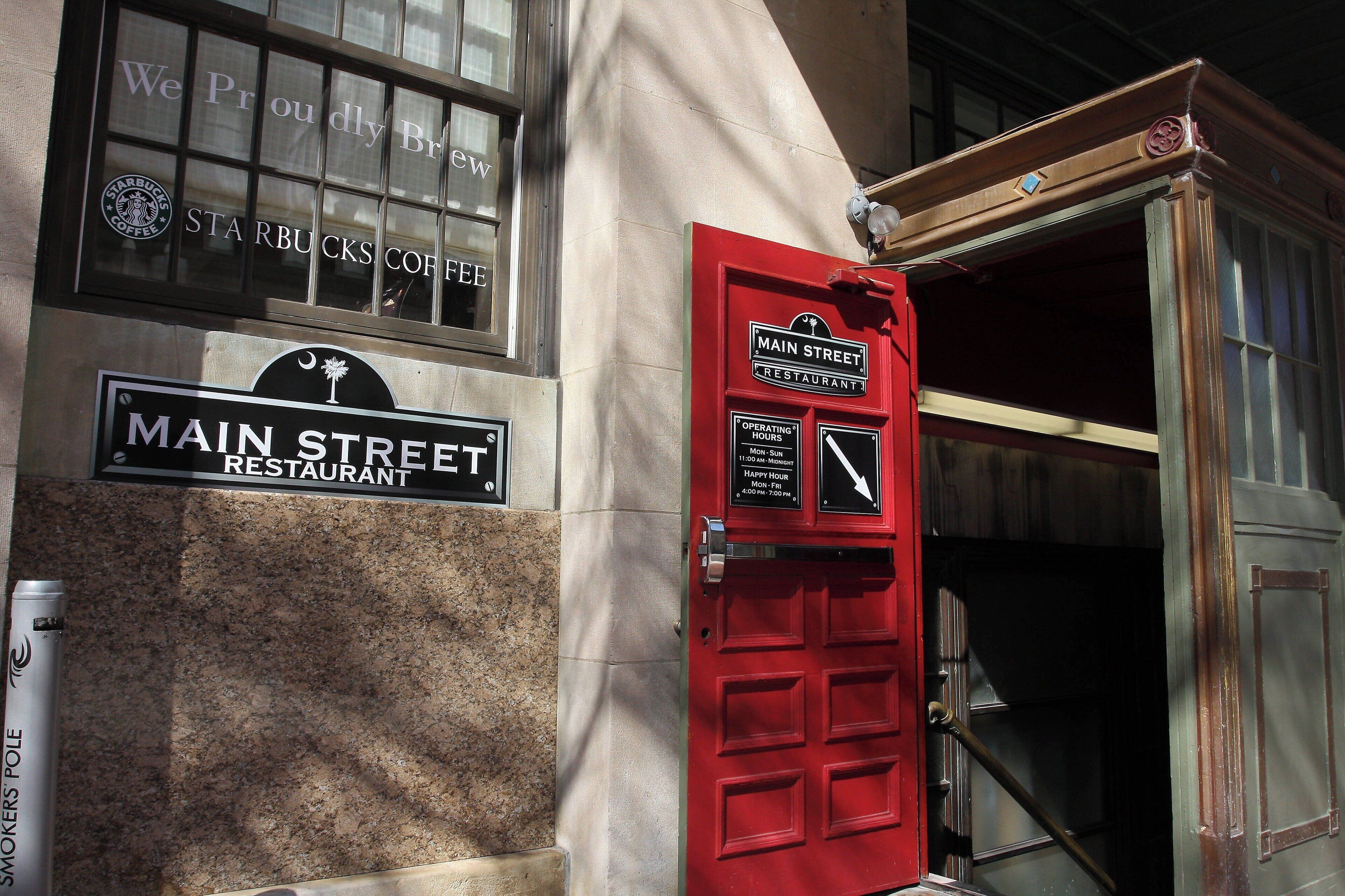 A building with a sign for 'Main Street Restaurant' and a red door with operating hours.