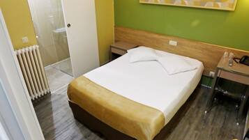 A hotel room with a bed, a bedside table, a nightstand, a mirror, and a radiator.