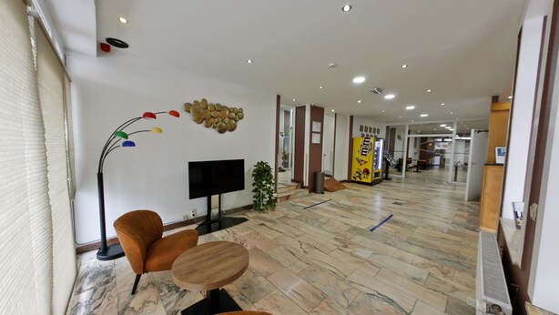 A modern hotel lobby with a marble floor, a flat-screen TV, a plant, and a vending machine. - Hotel de France (Brussels)