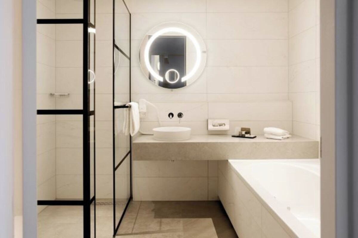 Une salle de bain moderne avec un miroir rond, un lavabo et une baignoire.