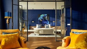 A modern living room with a large window, a sofa, a coffee table, and a painting of birds on the wall.