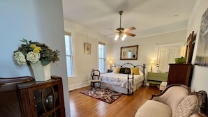 A bedroom with a bed, a chair, a dresser, and a ceiling fan.
