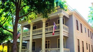 A two-story building with a balcony, columns, and flags.