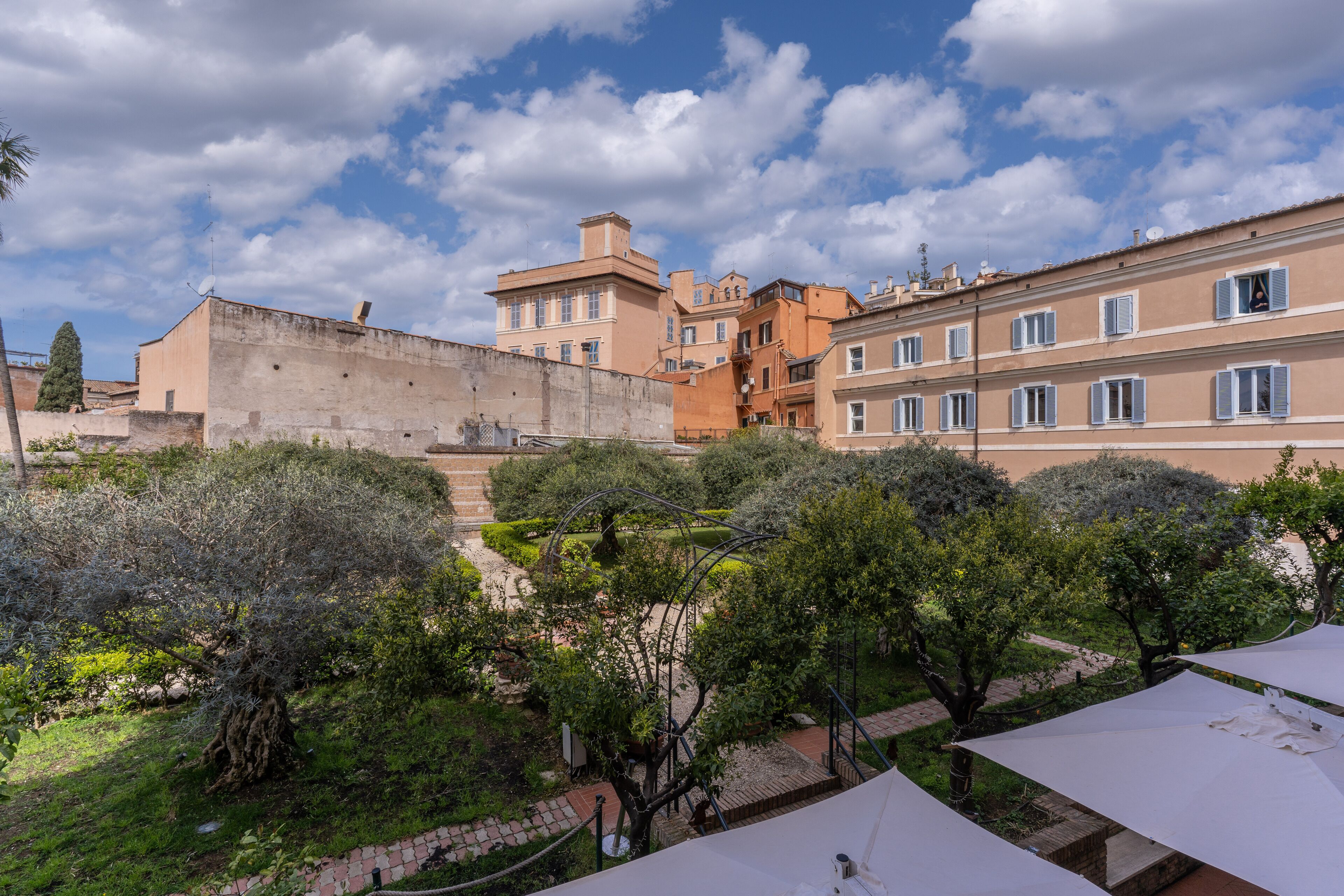 A courtyard with a garden, a pathway, and buildings with multiple windows and balconies.