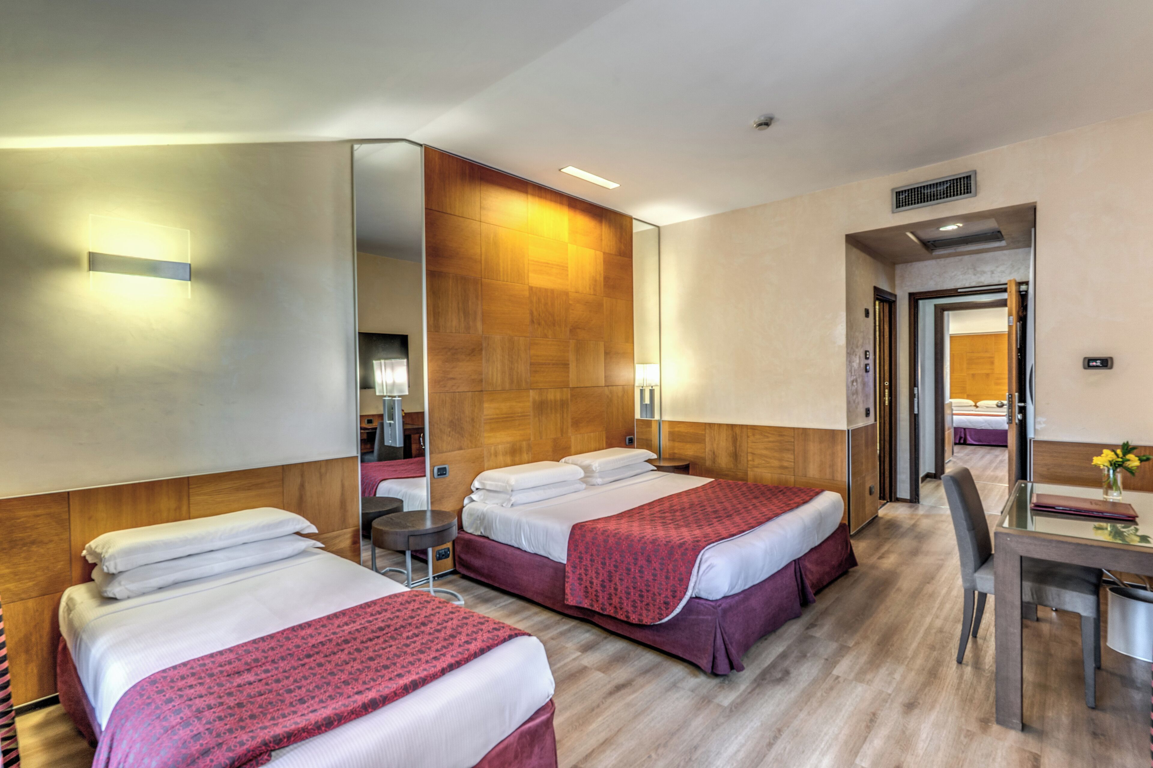 A hotel room with two beds, a desk, and a chair.