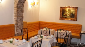 A dining area with tables set for two, a brick wall, and a framed painting on the wall. - Boutique Hotel Trevi (Rome)