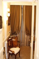 Una camera d'albergo con scrivania, sedia e finestra con tende.