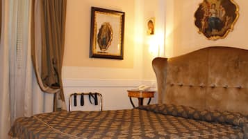 Camera d'albergo con un letto grande, una testiera, un comodino e un quadro appeso al muro.