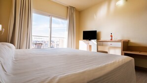 A hotel room with a large bed, a desk with a television, and a bottle of wine. - Hotel Fontana Plaza (Torrevieja)