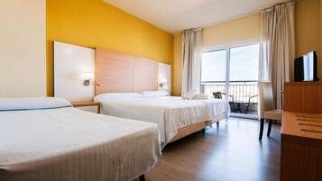 A hotel room with two beds, a TV, a balcony, and a desk.