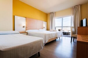 Quarto de hotel com duas camas, televisão, varanda e secretária.