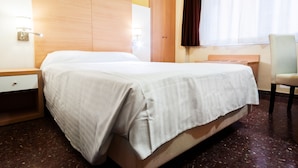A hotel room with a bed, a nightstand, a chair, a wardrobe, and a window with curtains. - Hotel Fontana Plaza (Torrevieja)