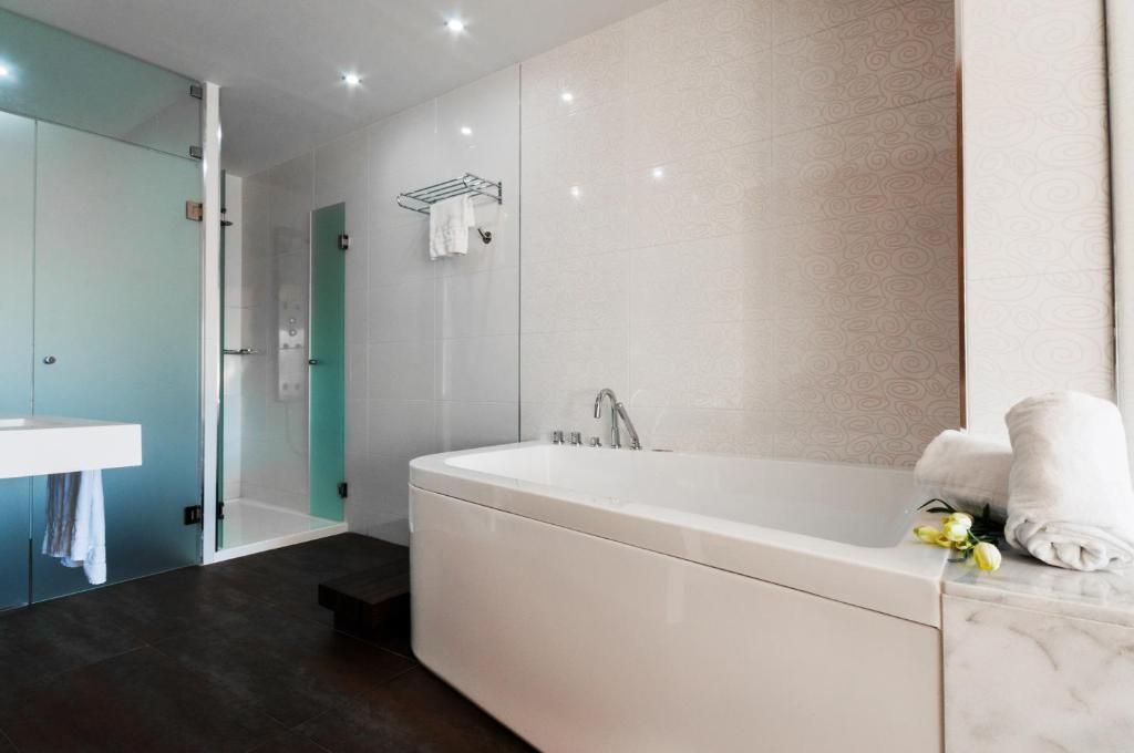 Un bany modern amb una banyera gran, un espai de dutxa amb vidre i un lavabo blanc.