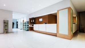 A modern reception area with a glass display case, a wooden reception desk, and a white tiled floor.