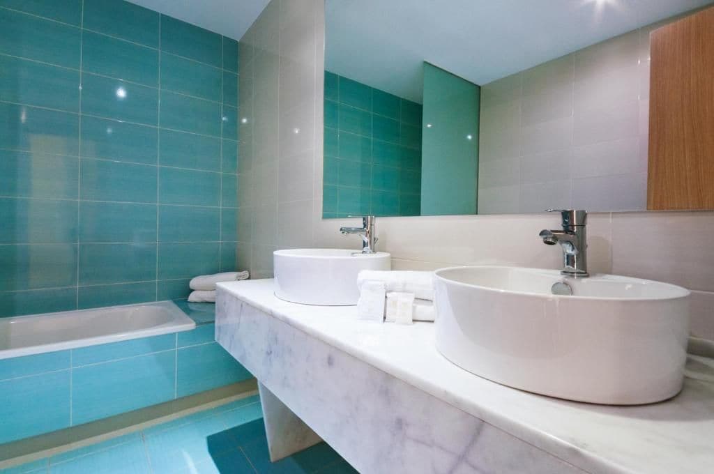 Une salle de bain avec deux lavabos, une baignoire et un grand miroir.