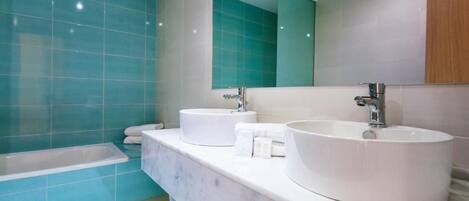 Une salle de bain avec deux lavabos, une baignoire et un grand miroir.