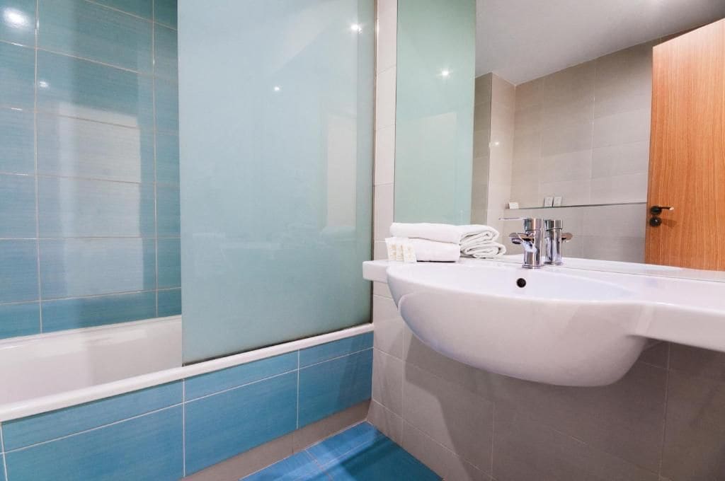 A bathroom with a bathtub, a sink, and a mirror.