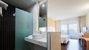 A hotel bathroom with a glass shower enclosure, a sink with a white basin, and a mirror. - Hotel Fontana Plaza (Torrevieja)