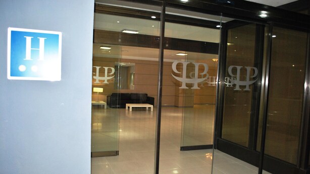 A hotel entrance with a glass door, a bench inside, and a visible logo on the wall. - Hotel Fontana Plaza (Torrevieja)