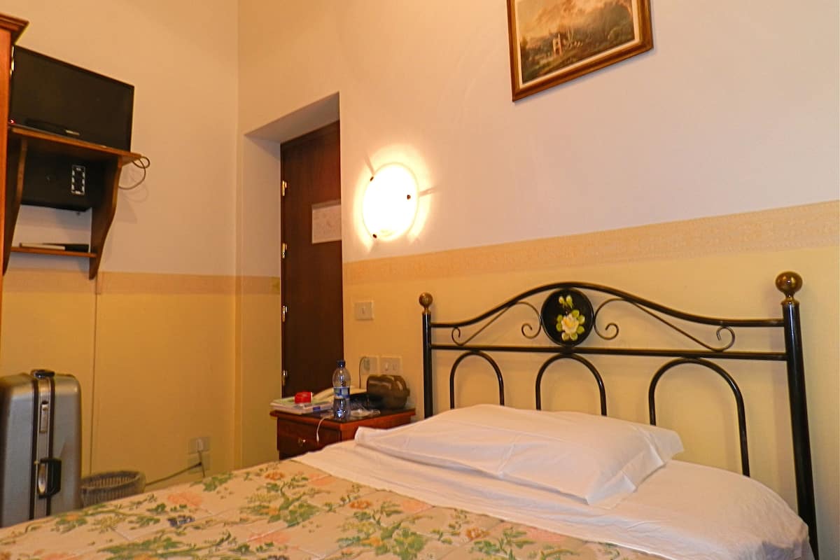 Une chambre d’hôtel avec un lit, un bureau, une chaise, une lampe et un tableau au mur.