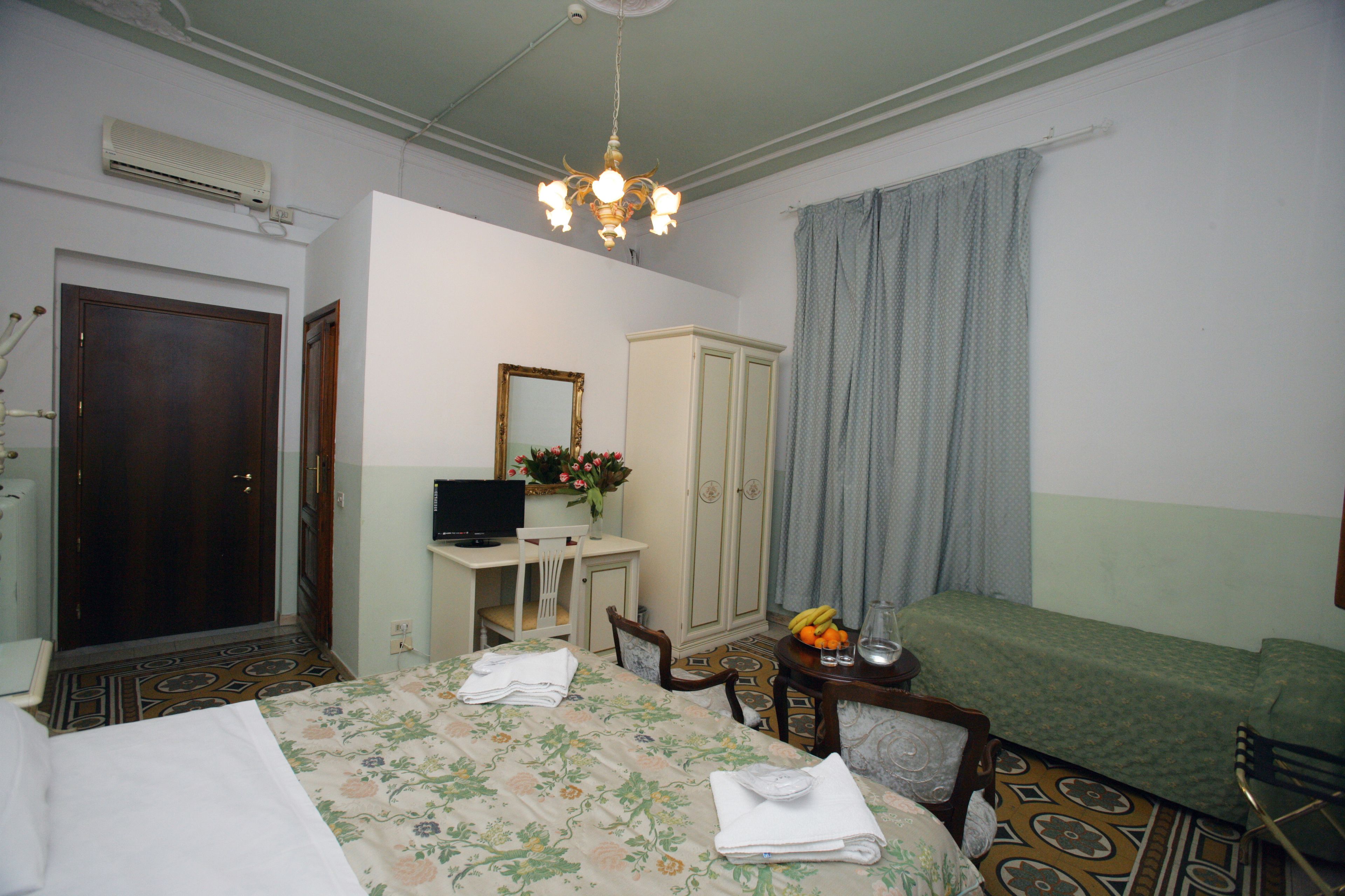 Una habitación de hotel con cama, escritorio, silla, armario y televisor.