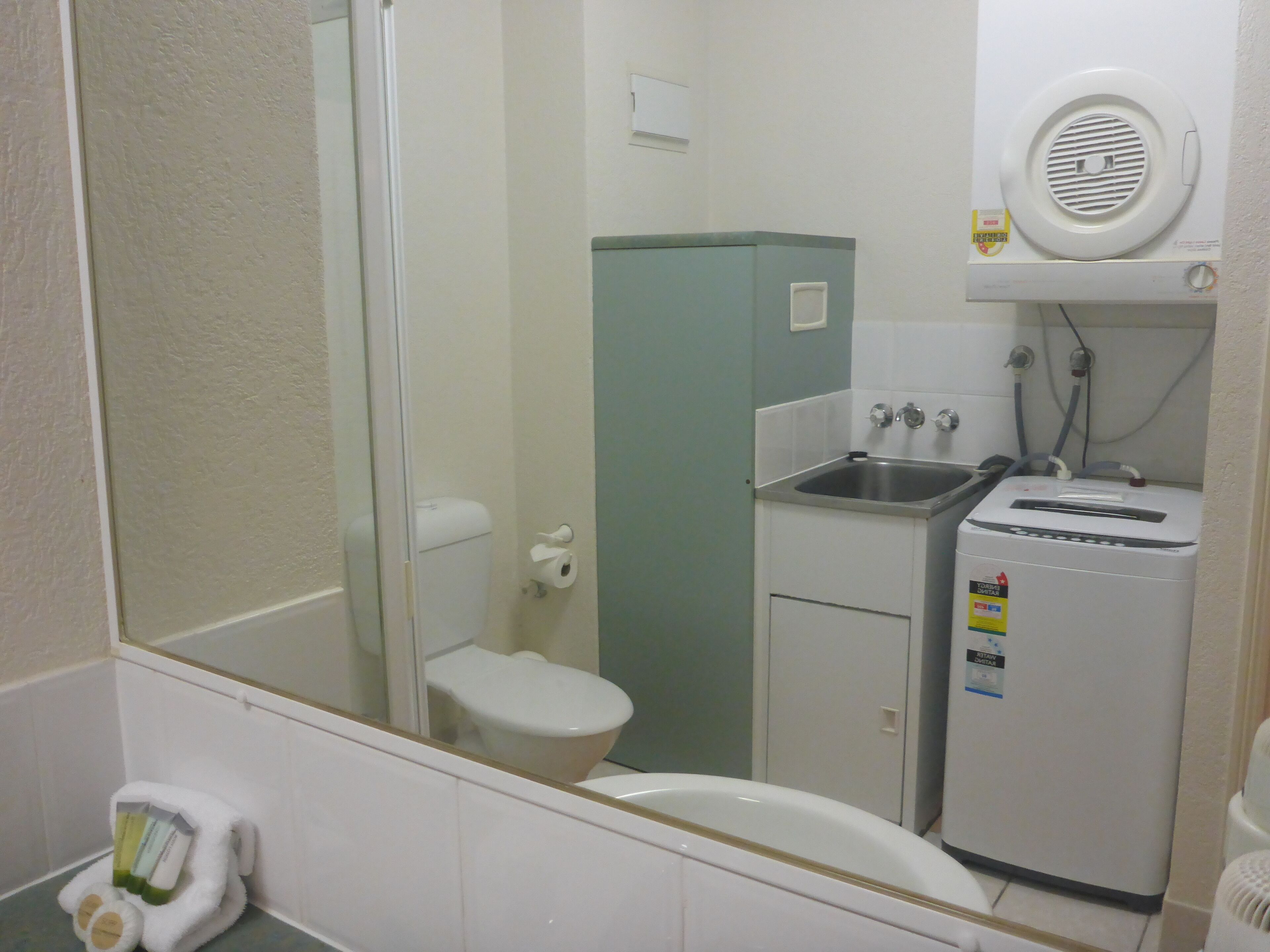 A compact bathroom with a toilet, sink, and a small refrigerator.