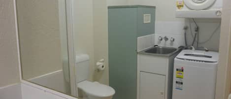 A compact bathroom with a toilet, sink, and a small refrigerator.