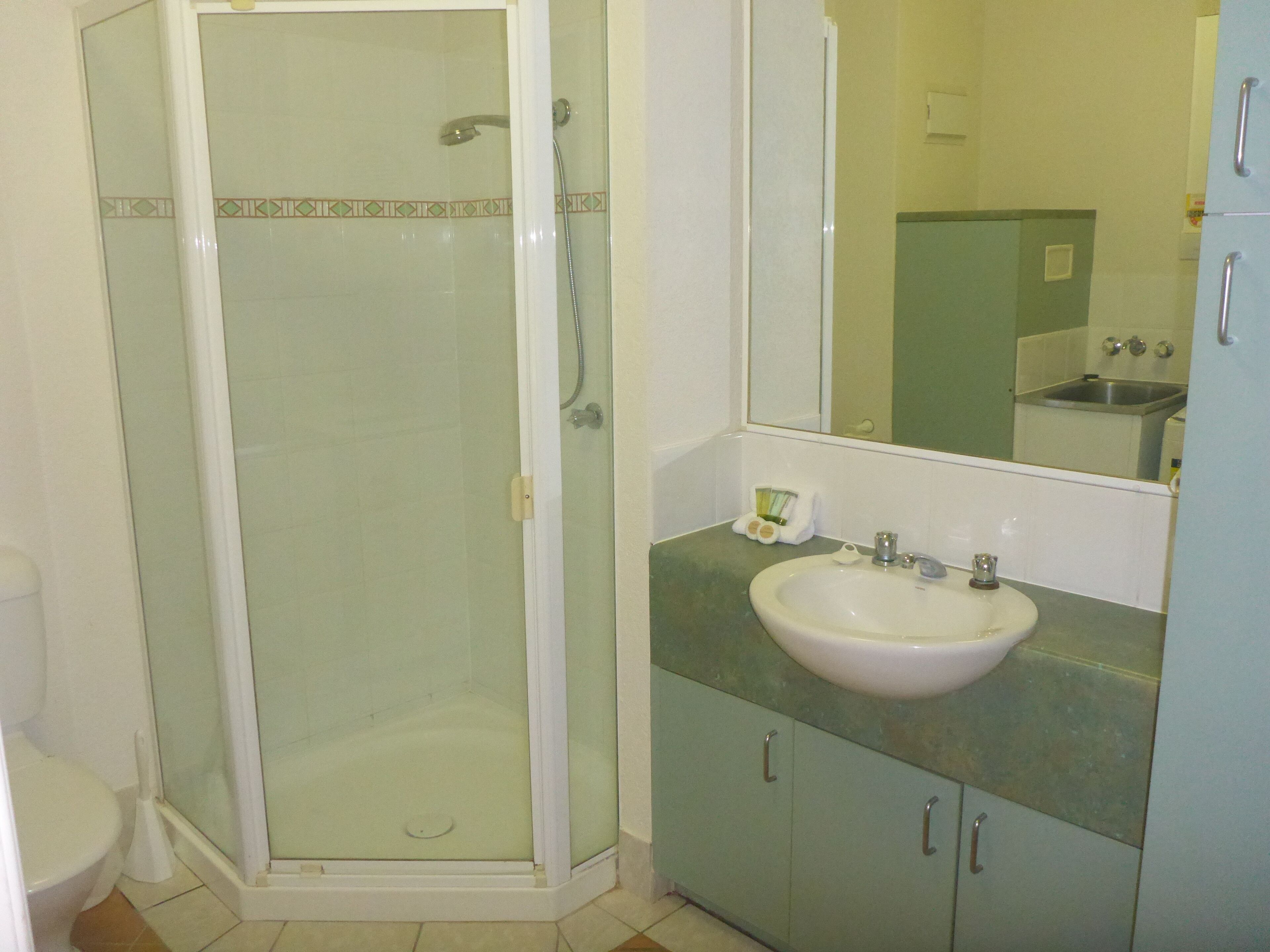 Une salle de bain avec une douche en verre, un lavabo et des placards.