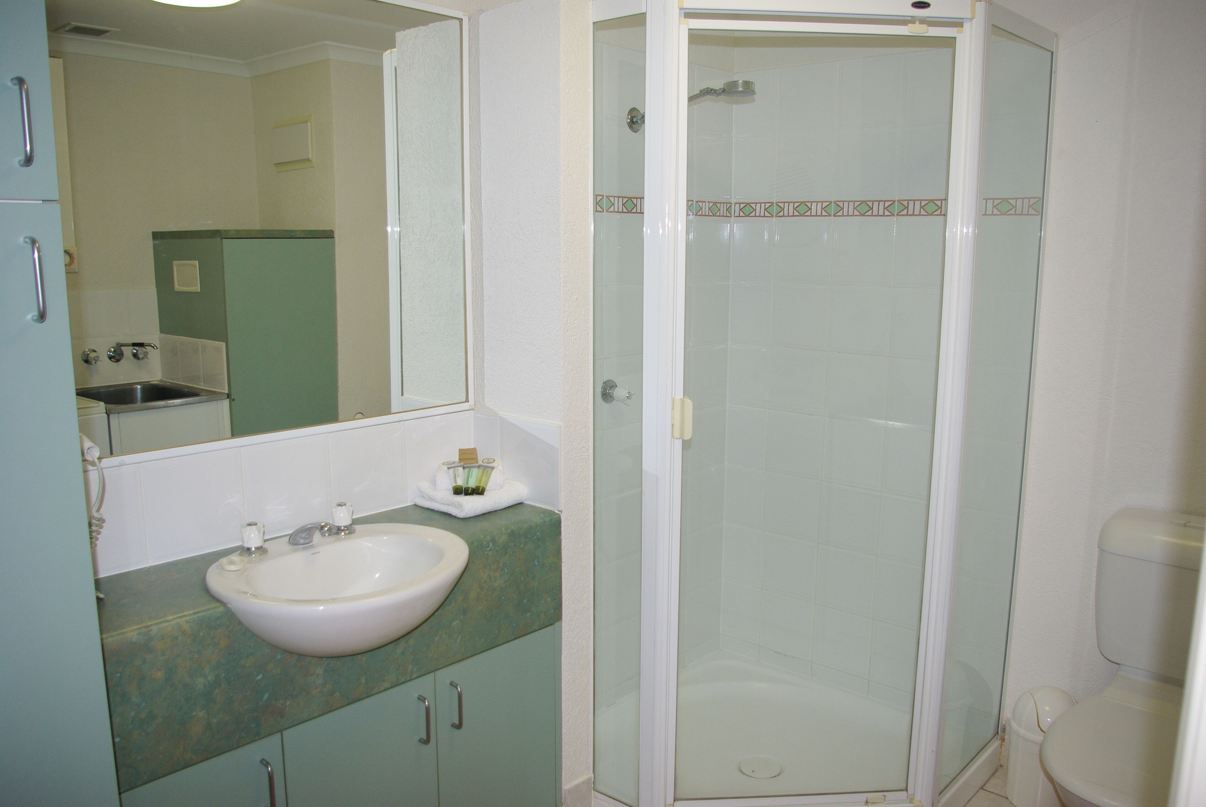 A bathroom with a sink, mirror, and glass-enclosed shower.