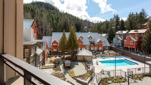 A residential area with a swimming pool, red and white houses, and a forested mountain backdrop.