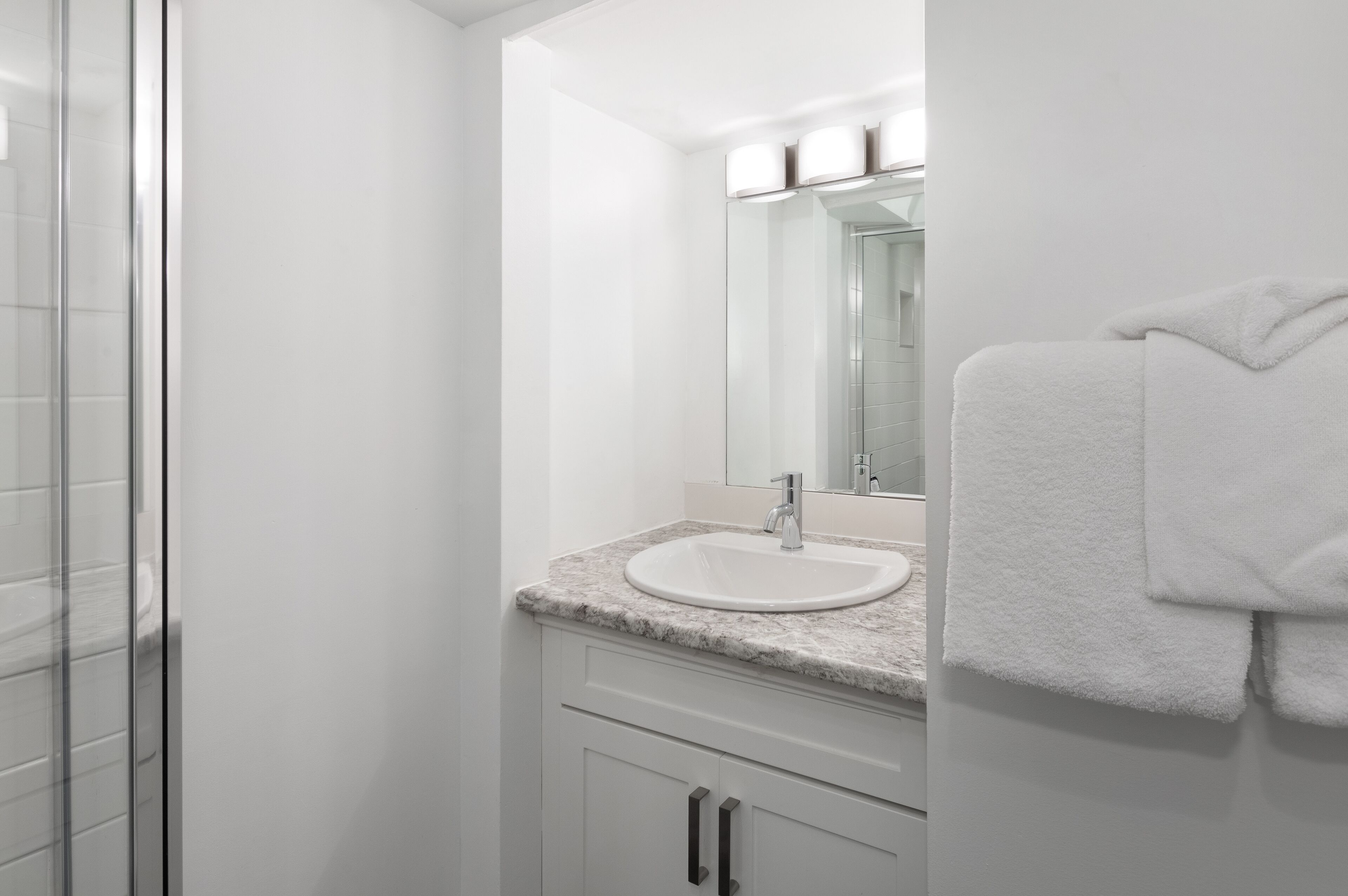 A bathroom with a white sink, a mirror, and a towel rack.