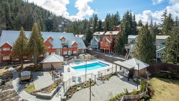 A resort with a swimming pool, multiple buildings, and a mountainous backdrop.