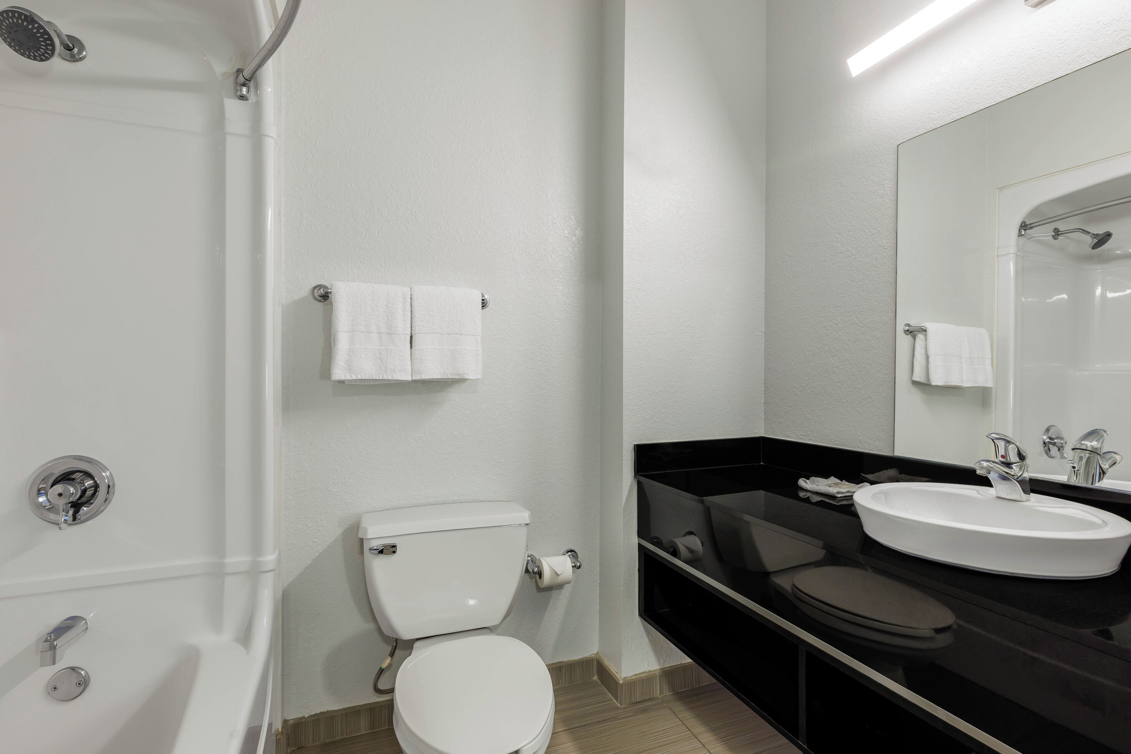 A modern bathroom with a white toilet, a black sink, and a shower.