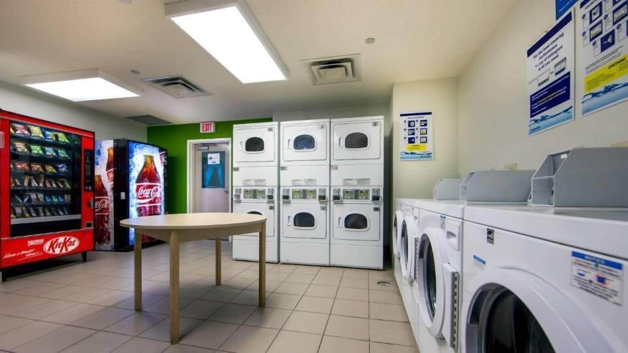 A laundromat with vending machines, a table, and stacked washing machines.