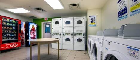 A laundromat with vending machines, a table, and stacked washing machines.